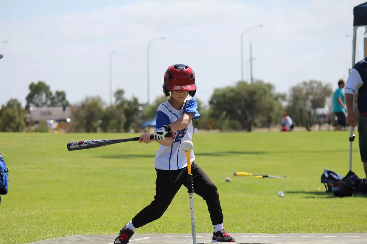 Young child takes a swing at the ball during a friendly game of tee ball